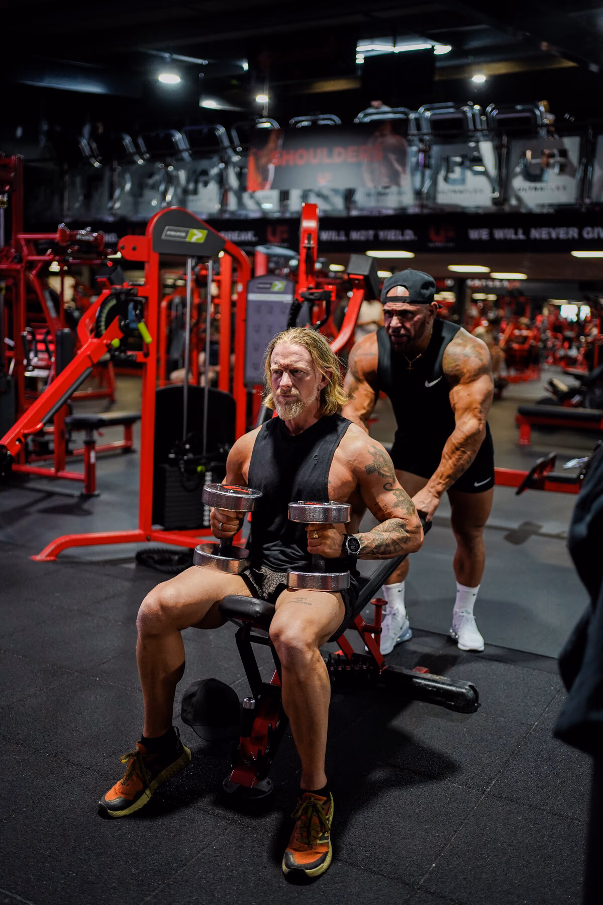 A coach cueing a client mid-set on dumbbells
